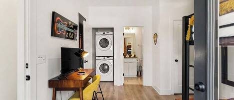 A compact living space with a dining area, a washing machine, and a bunk bed.