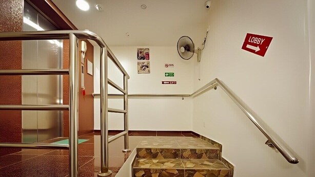 A hotel lobby with a staircase, a lobby sign, and a fire exit sign.
