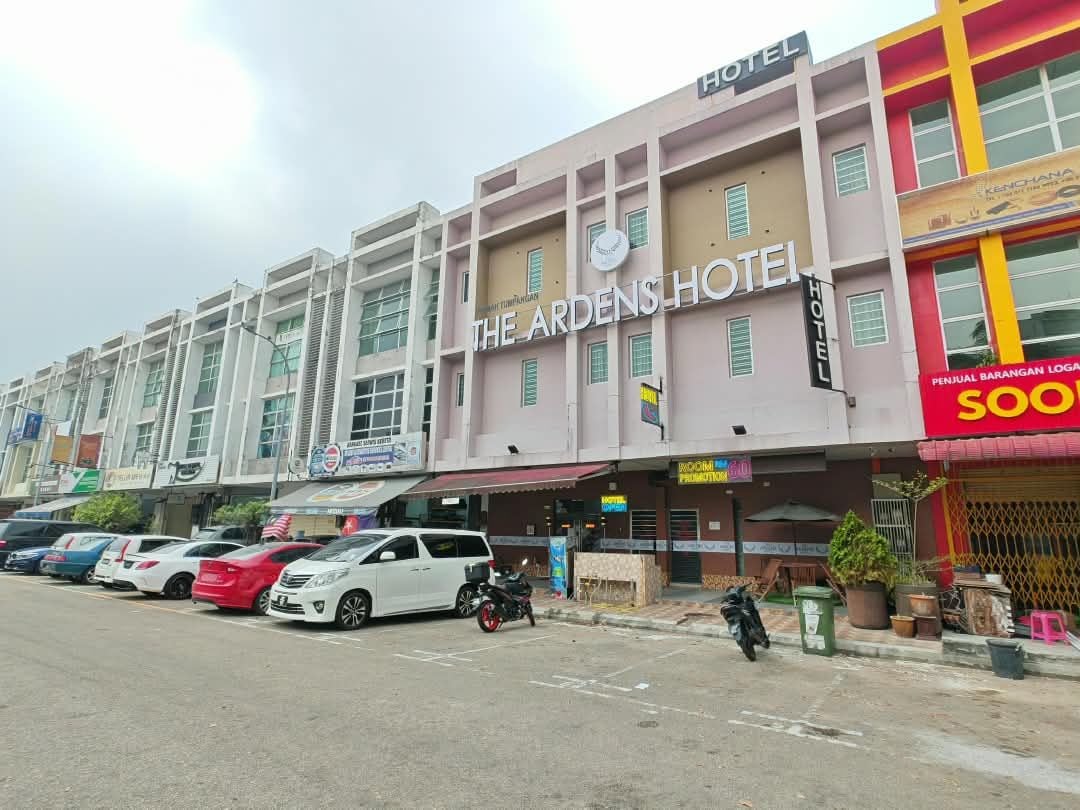 A hotel with a sign reading 'The Ardens Hotel' and a parking lot with several cars.