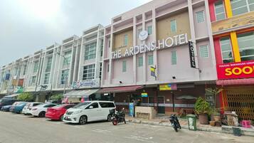 A hotel with a sign reading 'The Ardens Hotel' and a parking lot with several cars.