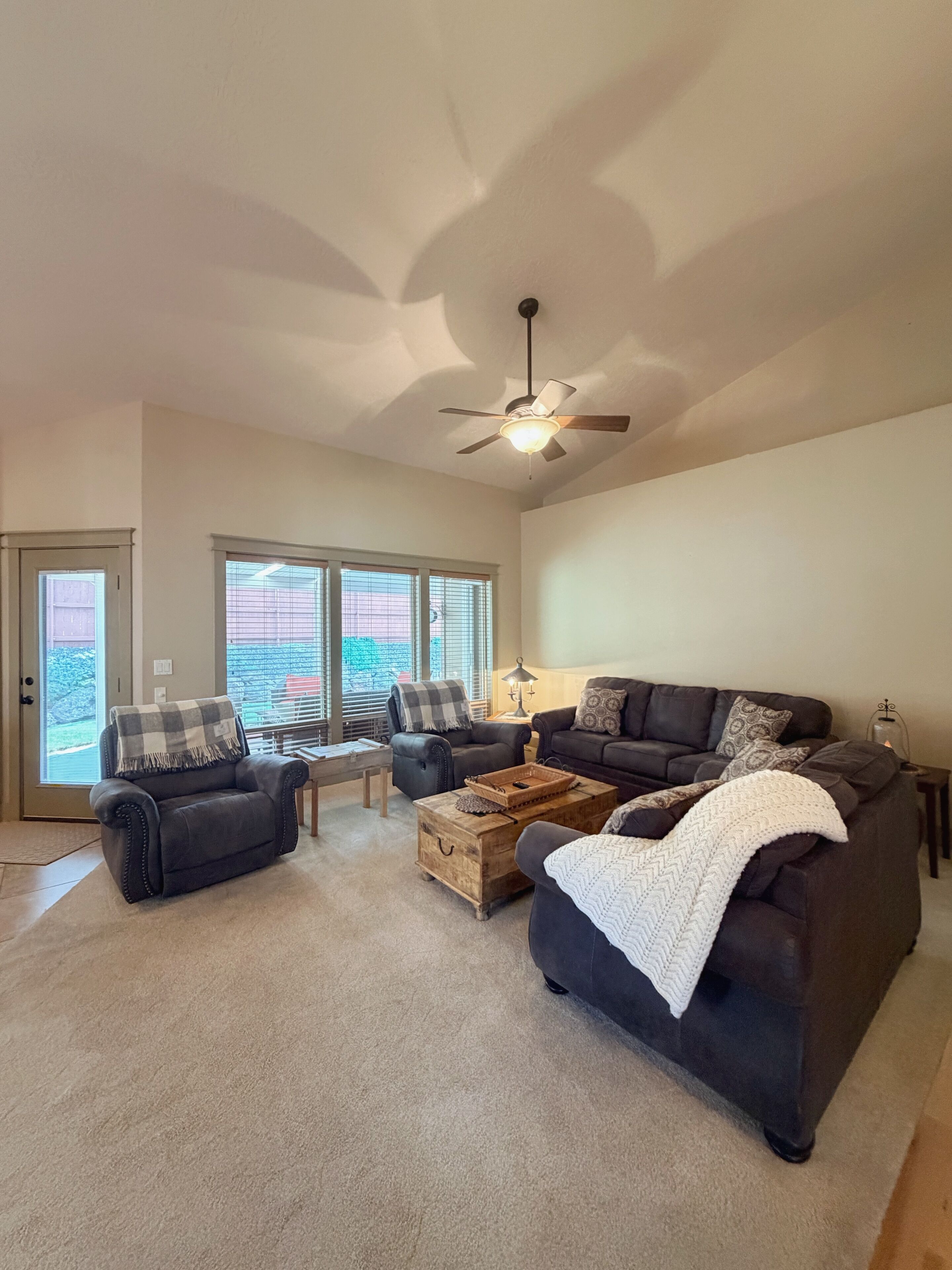 A living room with a ceiling fan, two sofas, a coffee table, and a window with blinds.