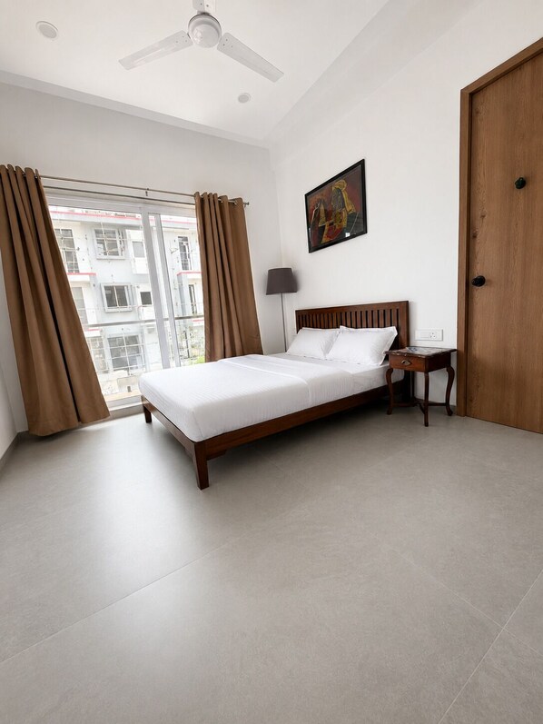 A hotel room with a bed, a nightstand, a lamp, a painting, and a door.