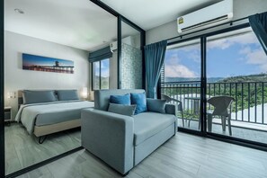 Ein Hotelzimmer mit Bett, einer Couch, einem Balkon mit Stuhl und einem Bild an der Wand.