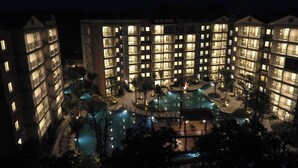 Un hotel de varios pisos con área de piscina, que incluye una piscina, sillas de descanso y una pequeña terraza.