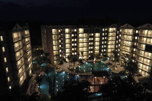 Ein mehrstöckiges Hotel mit Poolanlage, einschließlich Pool, Liegestühlen und einer kleinen Terrasse.
