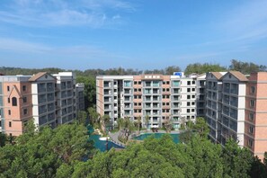Un hotel de varios pisos con un patio central que cuenta con una piscina, rodeado de exuberante vegetación.