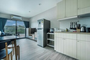 A modern kitchen with a built-in microwave, refrigerator, and a dining area with a view. - The Title Residencies Naiyang Beach Apartment G507 (Thalang/Sakhu)