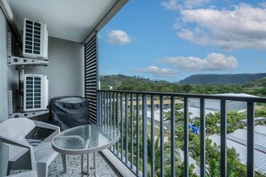 A balcony with two air conditioning units, a glass table, and a chair. - The Title Residencies Naiyang Beach Apartment G507 (Thalang/Sakhu)