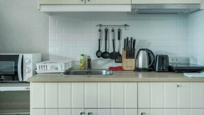 Una cocina con armarios blancos, microondas, tostadora, hervidor y varios utensilios en la encimera.