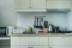 Eine Küche mit weißen Schränken, einer Mikrowelle, einem Toaster, einem Wasserkocher und verschiedenen Küchenutensilien auf der Arbeitsfläche.