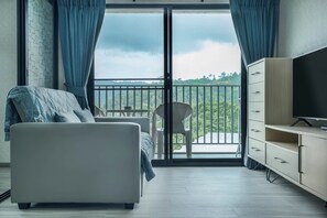 A modern hotel room with a balcony, a sofa, a TV, and a cabinet. - The Title Residencies Naiyang Beach Apartment G507 (Thalang/Sakhu)