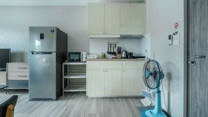 Une cuisine de taille réduite équipée d’un réfrigérateur, d’un four à micro-ondes et d’un ventilateur bleu.