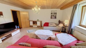 A living room with a wooden ceiling, a television, a sofa, a bed, and a painting on the wall. - Vacation home JANIKE by Interhome (Regensburg)