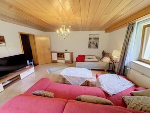 A living room with a wooden ceiling, a television, a sofa, a bed, and a painting on the wall. - Vacation home JANIKE by Interhome (Regensburg)