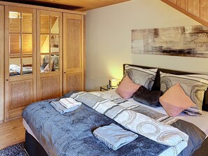 Ein Schlafzimmer mit einem Bett, Kissen, einem Nachttisch, einer Lampe und einem Holzschrank mit Glastüren.