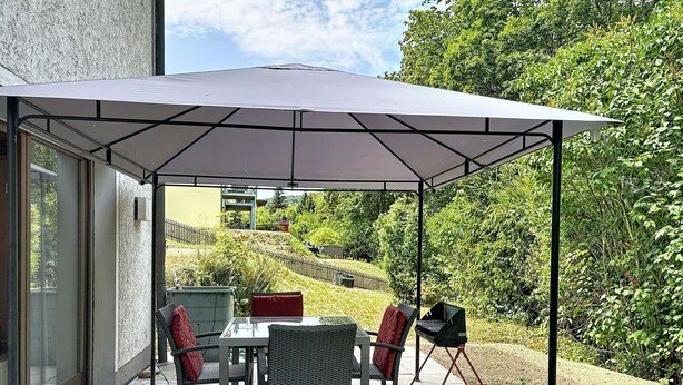 An outdoor patio area with a table and chairs, a grill, and a covered seating area. - Vacation home JANIKE by Interhome (Regensburg)