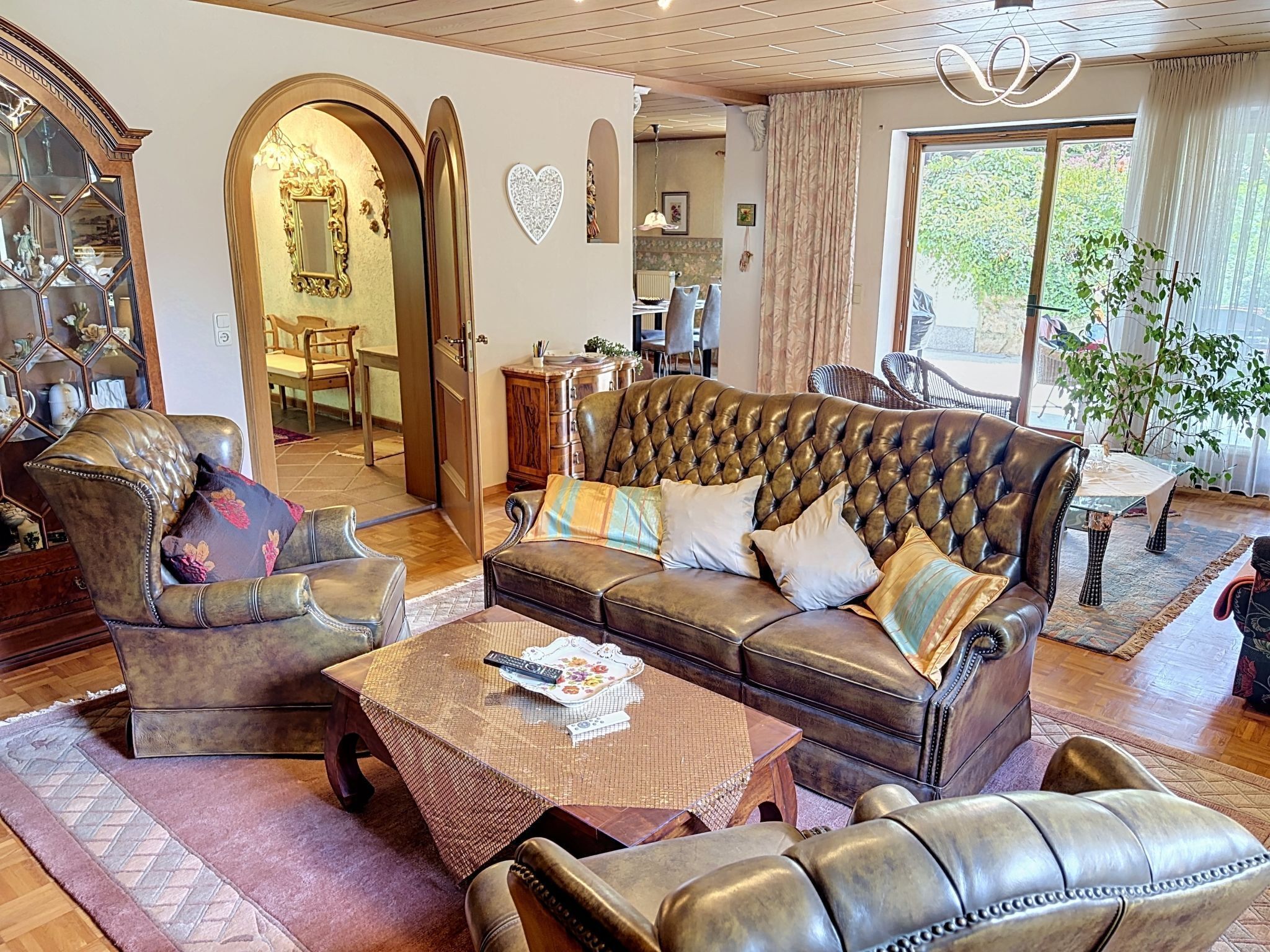 A spacious living room with a leather sofa, armchairs, and a coffee table.