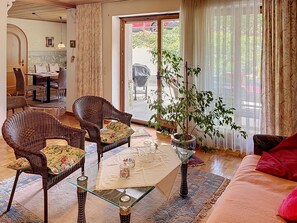A living room with wicker furniture, a glass coffee table, and a potted plant.