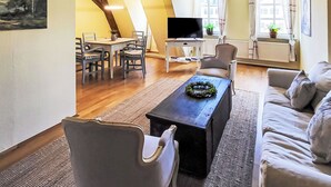 Una sala de estar con sofá, mesa de centro, televisor y un comedor con sillas y mesa.