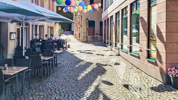 Una calle empedrada con mesas al aire libre y coloridos faroles de papel.
