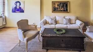 Una sala de estar con sofá, sillón y mesa de centro con un adorno floral.