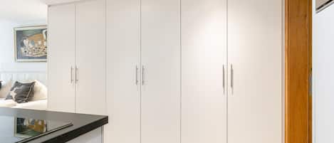 A modern kitchen with white cabinets, a black countertop, and a wooden door.