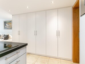 A modern kitchen with white cabinets, a black countertop, and a wooden door.