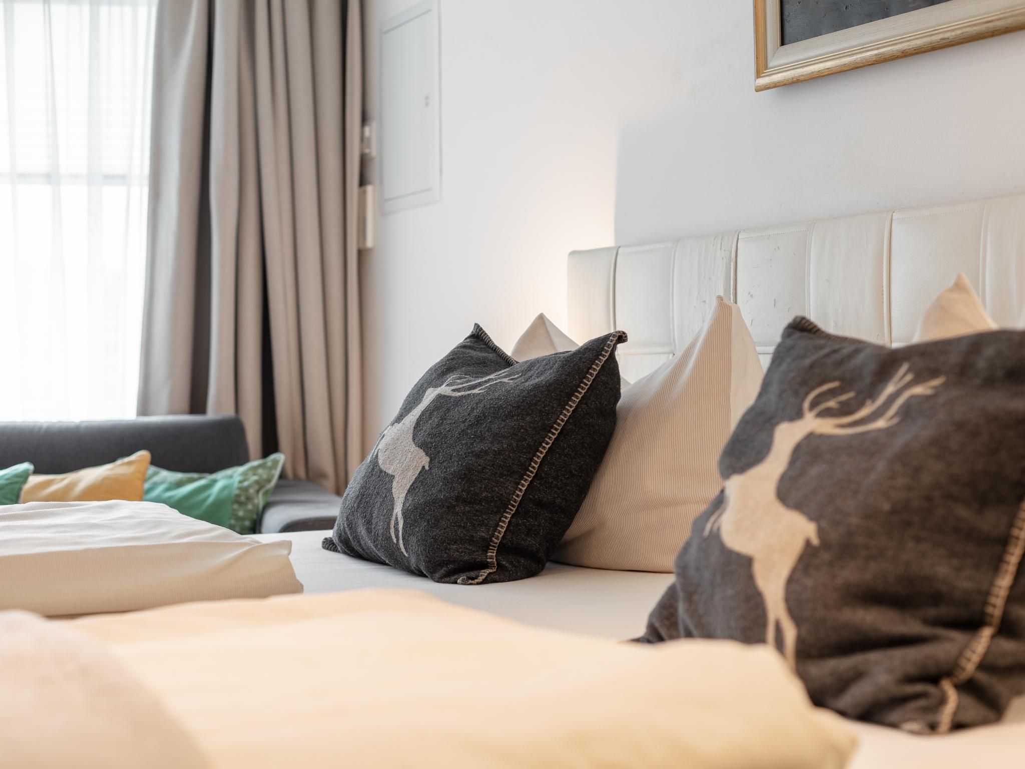 Ein ordentlich bezogenes Bett mit Kissen und einem weißen Kopfteil in einem Hotelzimmer.