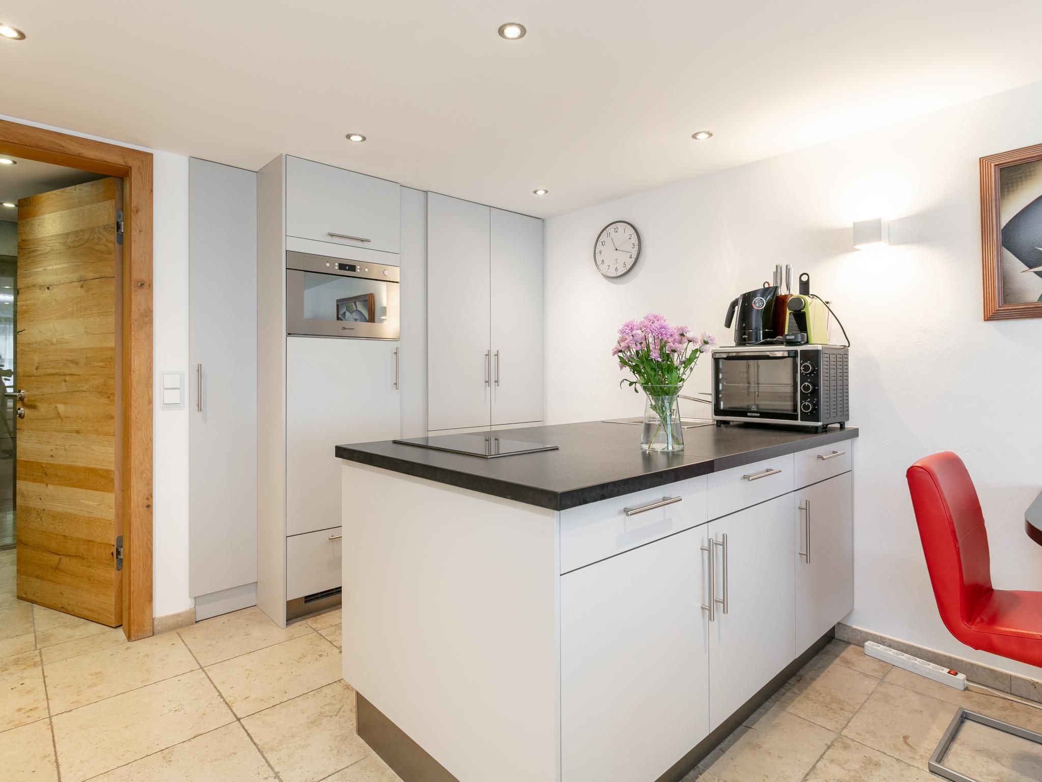 A modern kitchen with a built-in oven, microwave, and a coffee machine on the counter.