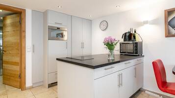 A modern kitchen with a built-in oven, microwave, and a coffee machine on the counter.
