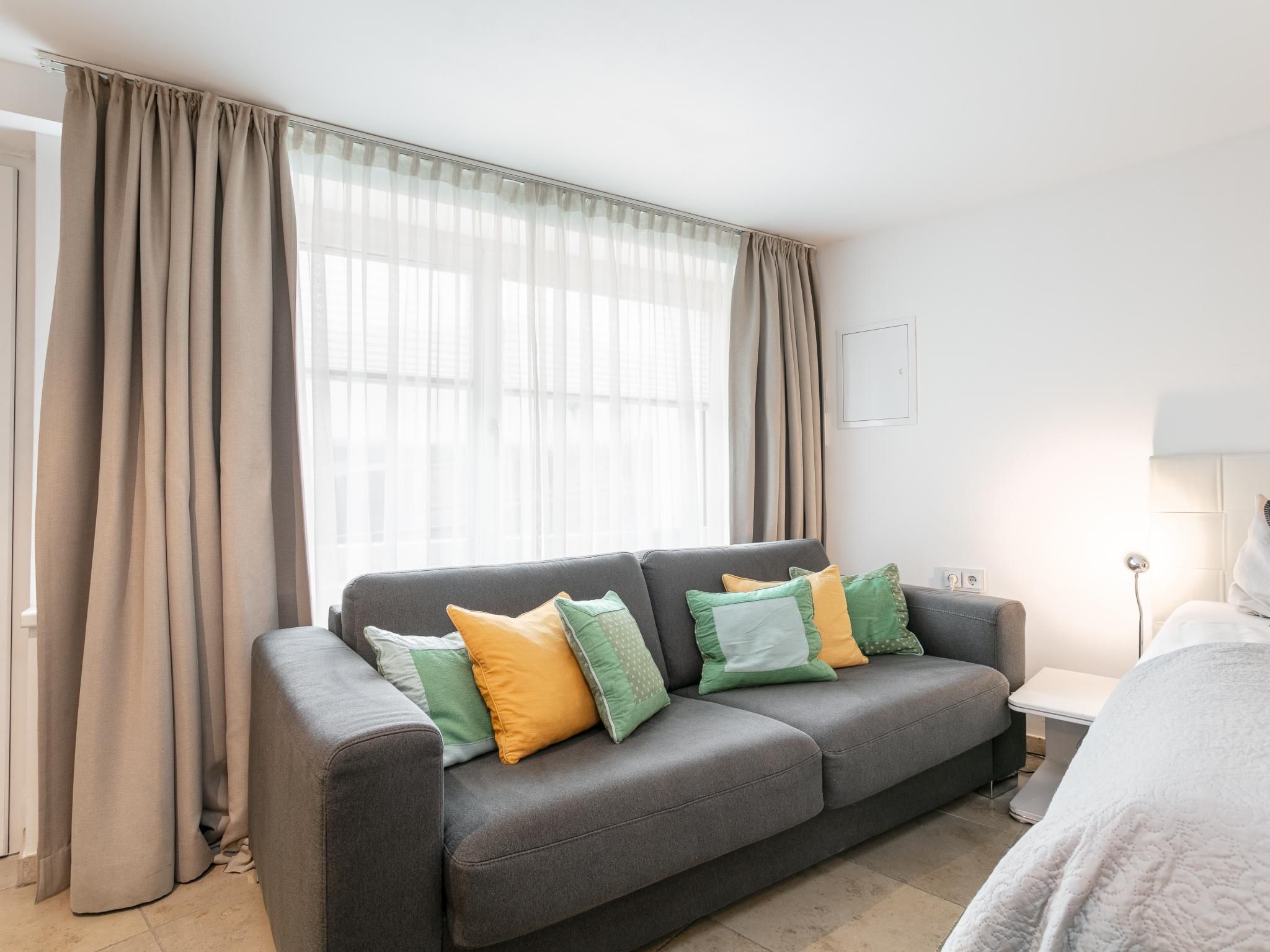 Una sala de estar moderna con un sofá gris, una mesita de noche y una lámpara.