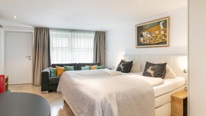 Ein modernes Schlafzimmer mit einem großen Bett, einer Couch, einem Esstisch und einem Gemälde an der Wand.