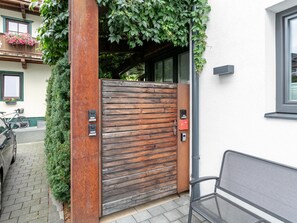 Una porta de fusta amb un mànec metàl·lic, una banca i una bicicleta aparcada a l'exterior.
