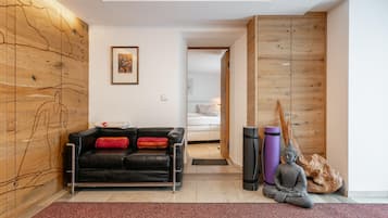 Una sala de estar moderna con un sofá de cuero negro, una pared de madera con un mapa, un cuadro enmarcado y una estatua de meditación.
