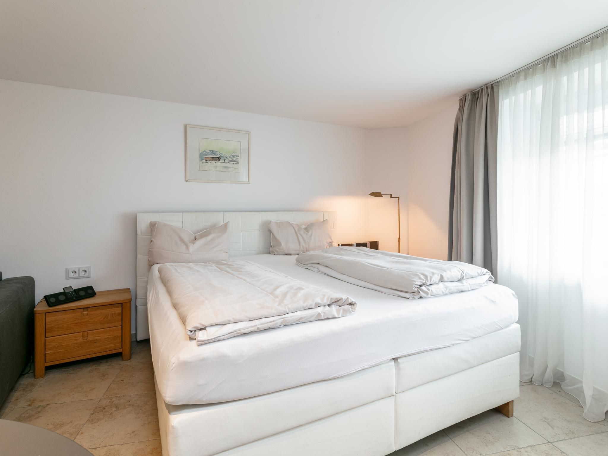 Een moderne hotelkamer met een groot bed, nachtkastjes, een lamp en een schilderij aan de muur.