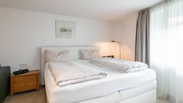 Een moderne hotelkamer met een groot bed, nachtkastjes, een lamp en een schilderij aan de muur.