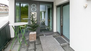 Ein moderner Gebäudeeingang mit Glastür, einem kleinen Tisch und einem Blumentopf.
