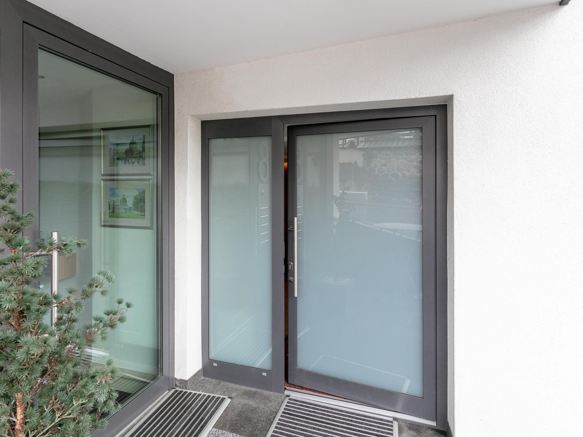 Une entrée moderne avec des portes en verre et un seuil en métal.