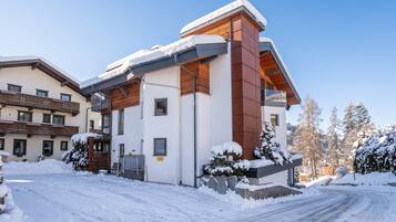 A modern building with a snow-covered roof and a paved driveway.