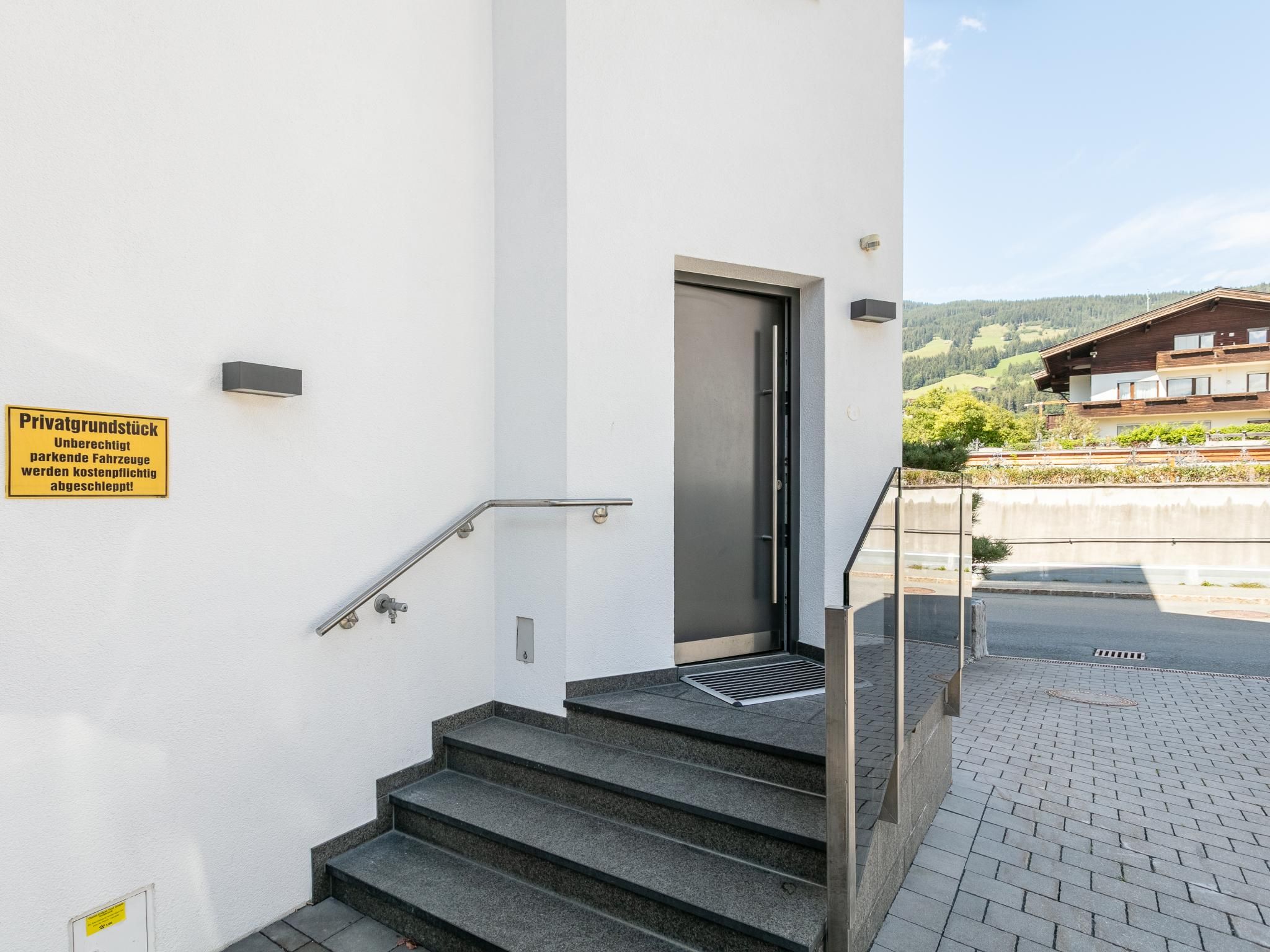 Una escalera conduce a una puerta con un cartel que indica acceso privado y restricciones de estacionamiento.