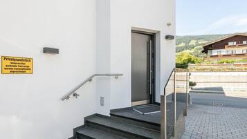 Una escalera conduce a una puerta con un cartel que indica acceso privado y restricciones de estacionamiento.