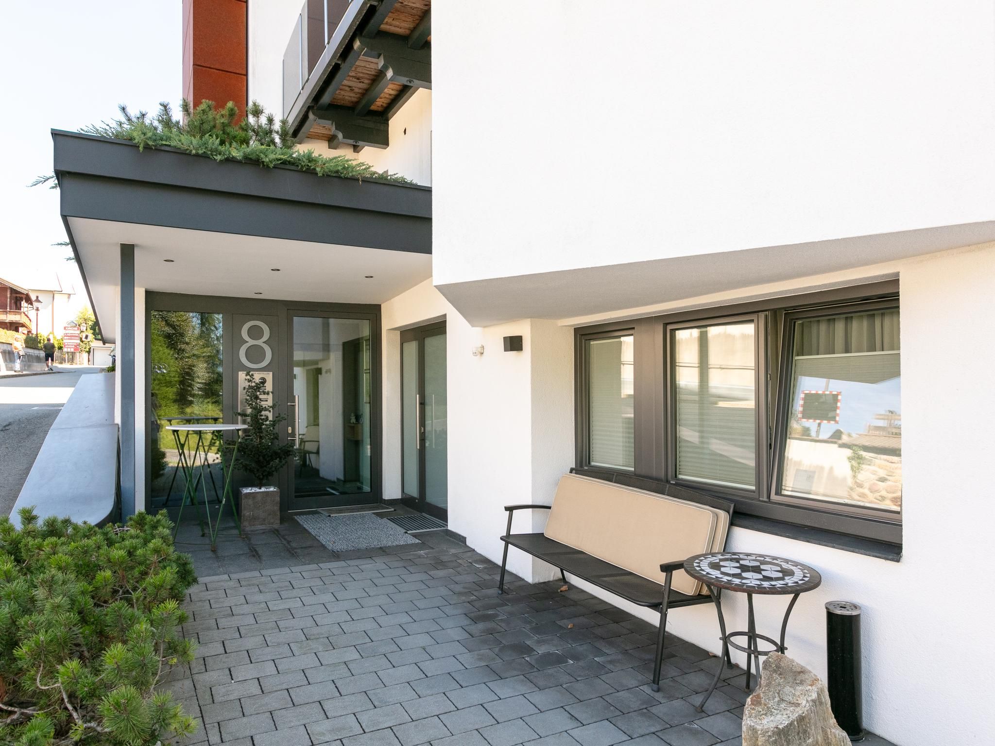 A modern building with a glass door entrance, a bench, and a small table outside.