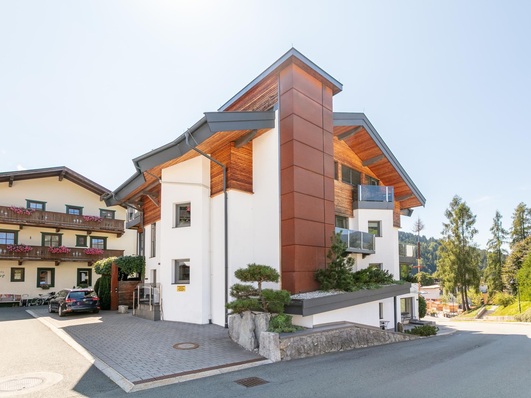 Een modern, twee verdiepingen hoog gebouw met een plat dak, grote ramen en een stenen fundering.