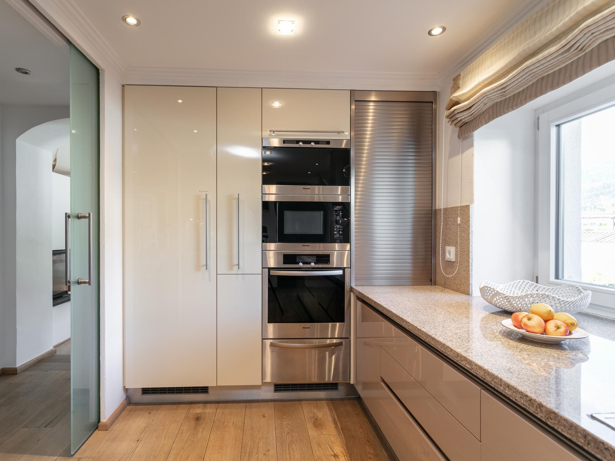 Una cocina moderna con electrodomésticos de acero inoxidable, un refrigerador con puerta de vidrio y una ventana con vistas.