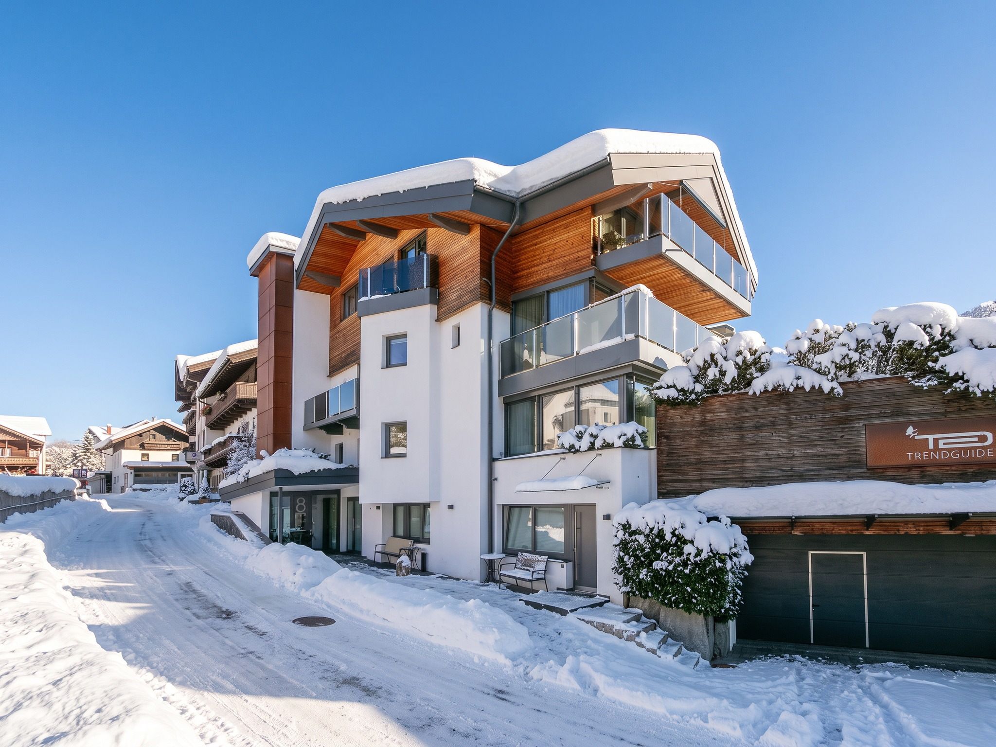 Een modern, meerhoog gebouw met een met sneeuw bedekte kap en balkons, omgeven door een besneeerd landschap.