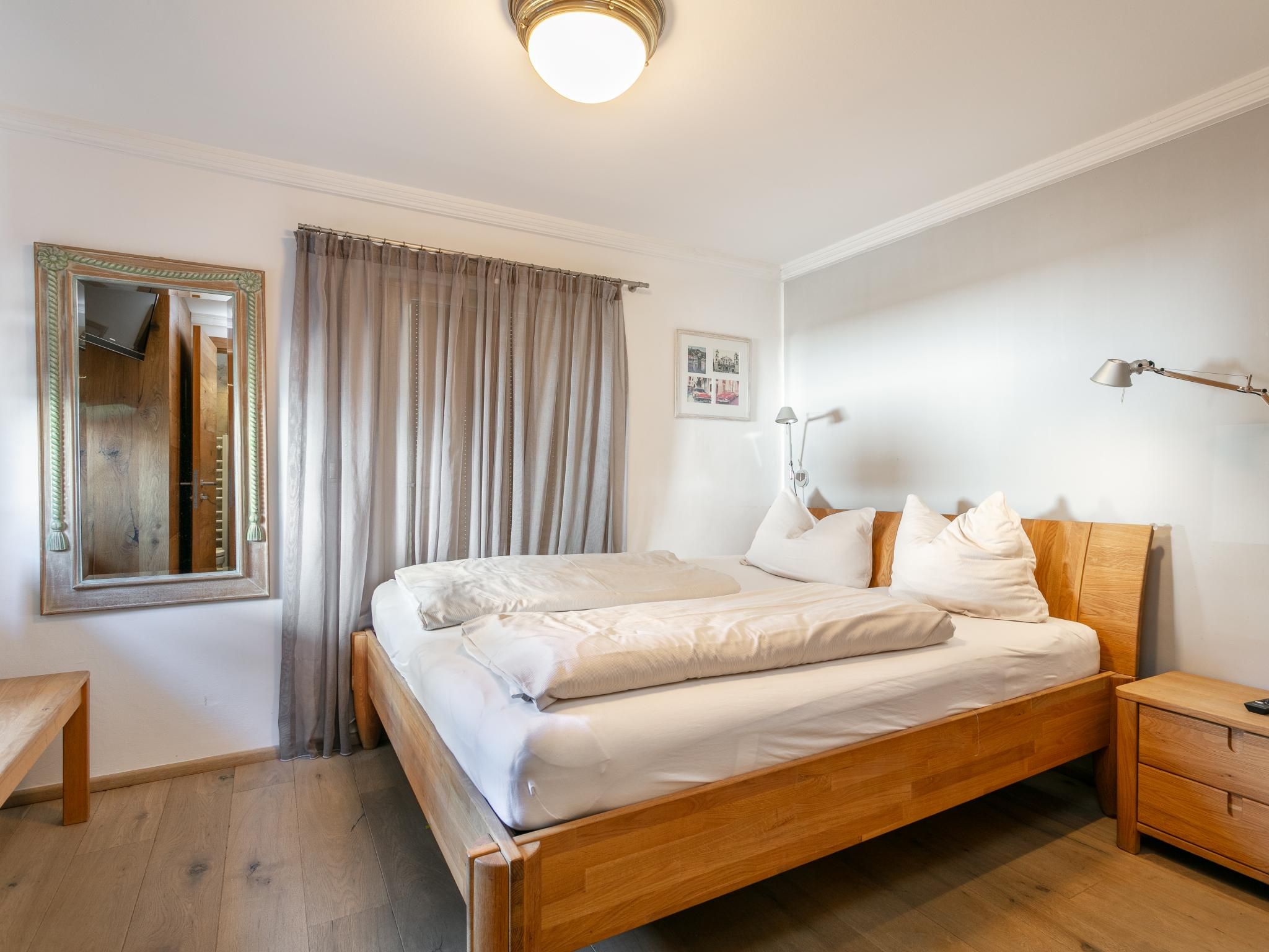 Un lit bien fait, avec du linge de lit blanc, une tête de lit en bois et une table de chevet avec une lampe.