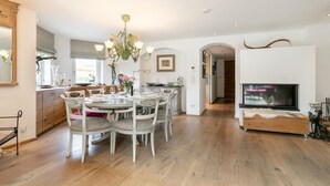 Eine moderne Küche mit Essbereich, Holzboden und einem Fernseher im Wohnzimmer.