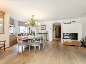 Eine moderne Küche mit Essbereich, Holzboden und einem Fernseher im Wohnzimmer.