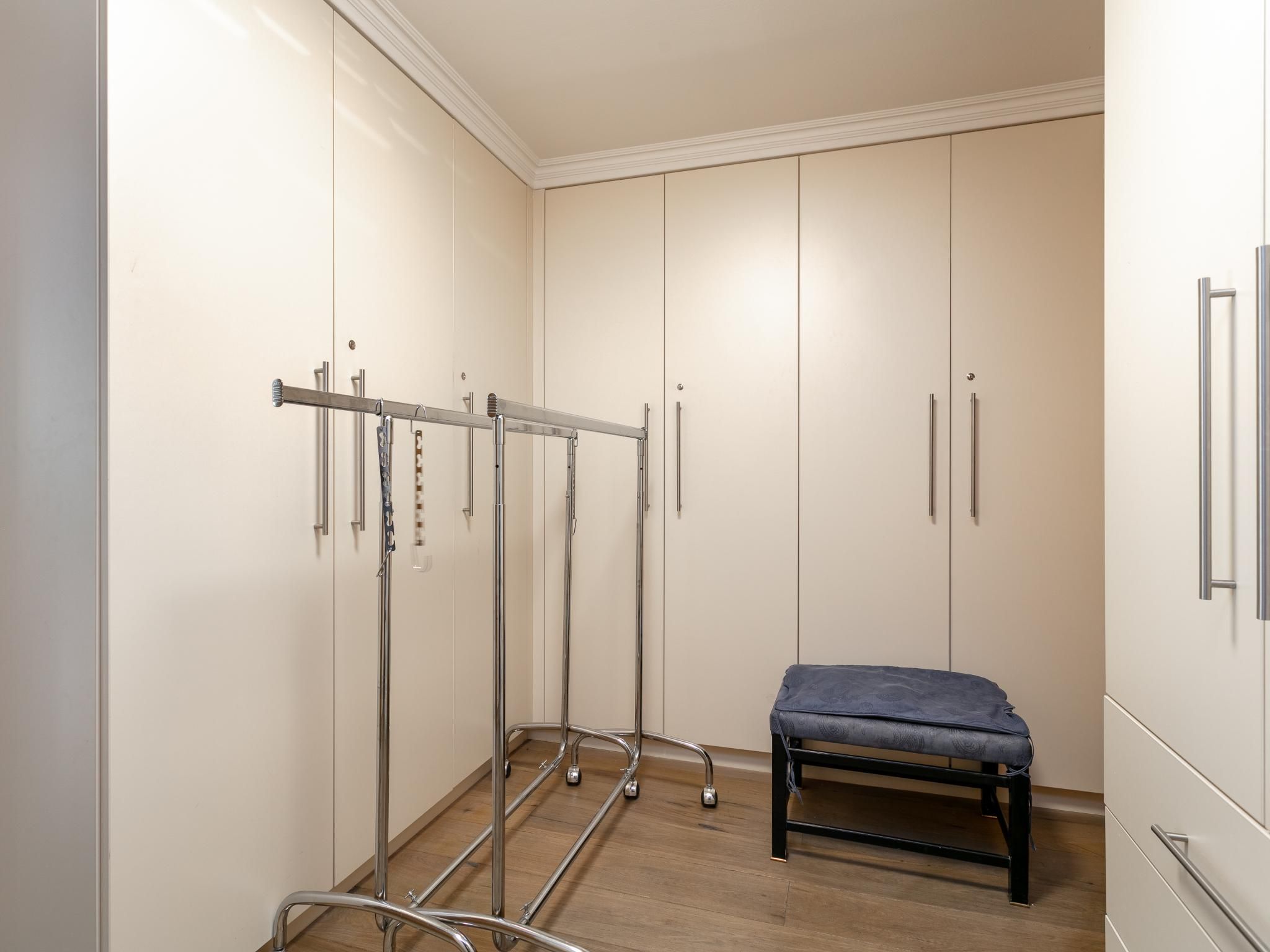 Una habitación con un banco, armario y un estante de metal con objetos.