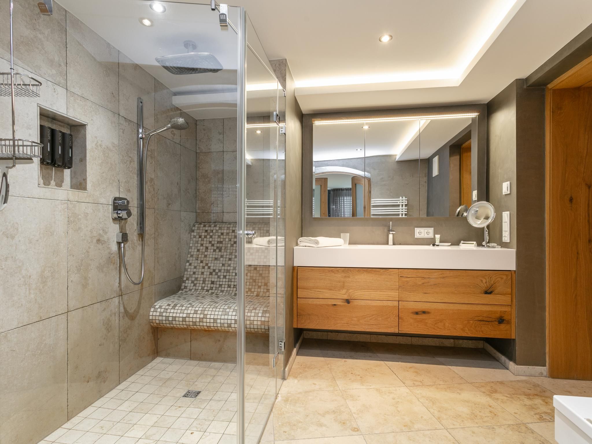 Une salle de bain moderne avec une douche à parois de verre, un meuble-lavabo avec un miroir et un placard en bois.